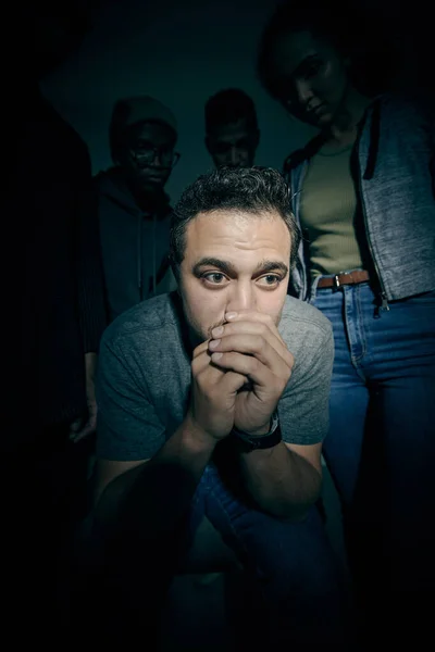 One mixed race male suffering mental illness in asylum. Caucasian schizophrenic man experiencing a depression while being surrounded by people on a stage theatre performance.