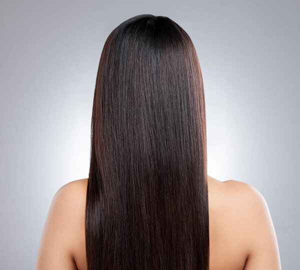 I love it all smooth and sleek. Rearview shot of a young woman with long silky hair posing against a grey background