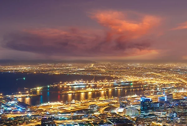 Scenic view of Cape Town at night from Signal Hill in South Africa. Beautiful landscape view of the city lights and buildings against a dark and cloudy evening sky. Popular tourist town at twilight.