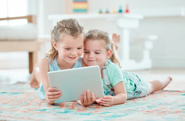 Two Adorable Girls Using Digital Tablet While Lying Floor Home — Stock fotografie
