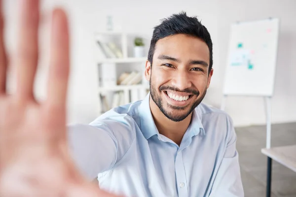 Portrait of a mixed race hispanic businessman making a frame shape gesture with his hands while smiling in a office. Cheerful hispanic male looking happy.