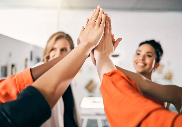 The higher we aim, the greater the success. a group of businesswoman giving each other a high five in an office at work