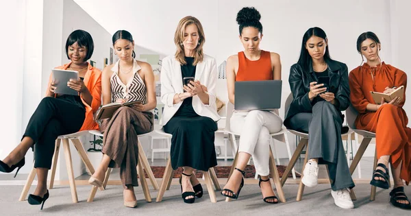 Lets get down to work. a group of businesswomen sitting in a row in an office at work