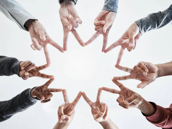 Below hands in circle making a star shape. A group of people putting their fingers together while standing in a huddle outside against a clear and bright sky. Anything is possible with teamwork.