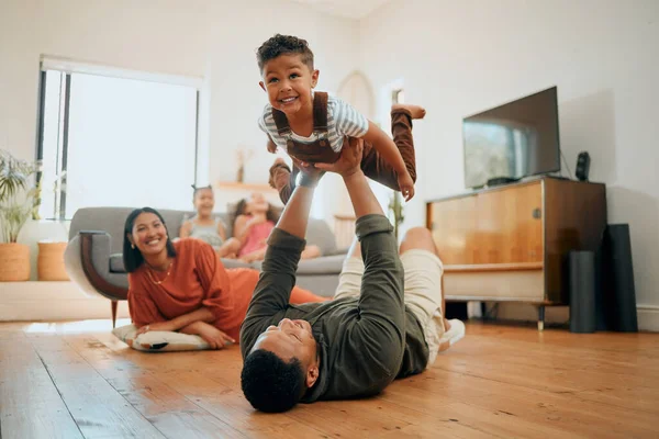 A happy mixed race family of five relaxing in the lounge and being playful together. Loving black family bonding with their son while playing fun games on the floor at home.