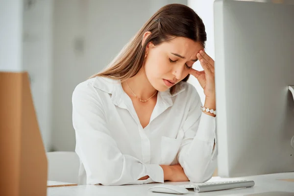 One anxious young hispanic business woman suffering with a headache while working on a computer in an office. Entrepreneur feeling overworked, tired and anxious about deadlines. Mentally frustrated