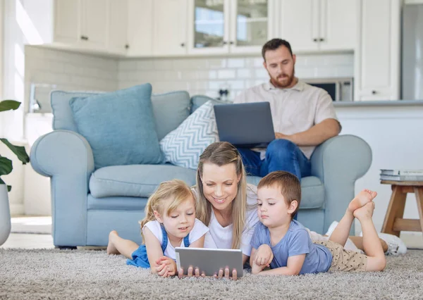 Mother and two kids watching something on digital tablet. Little girl and boy watching educational cartoon videos or on video call with tablet. Dad works from home.