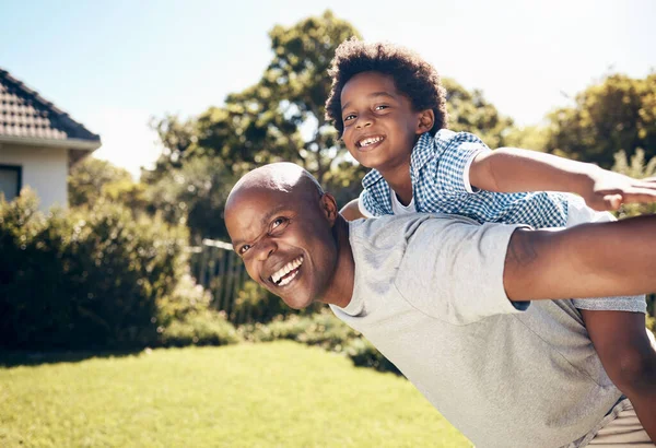 Portrait of a happy african american man bonding with his young little boy outside. Two black male father and son looking happy and positive while being affectionate and walking in a park.