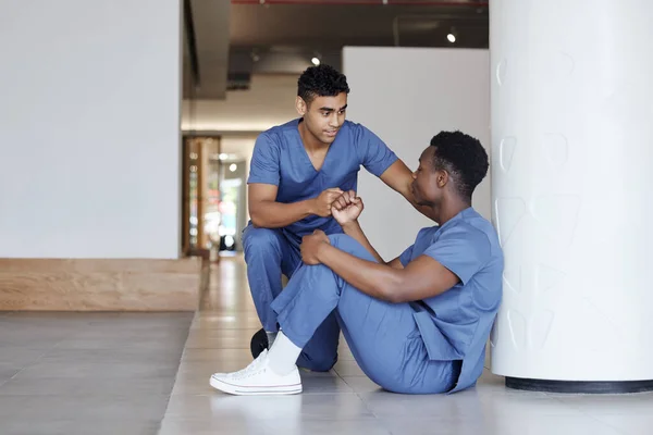 a young male doctor consoling a coworker at work.