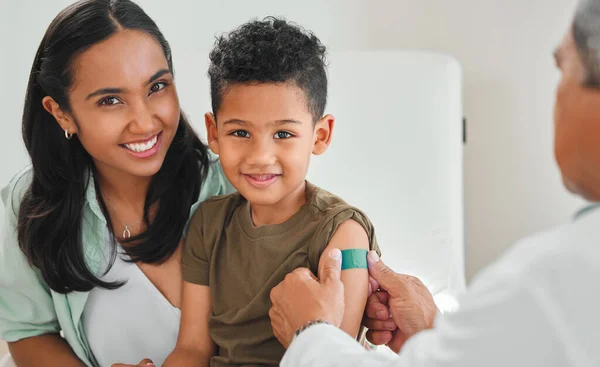 Protecting myself from all disease. a mature male doctor applying a bandaid to a little boys arm at a hospital