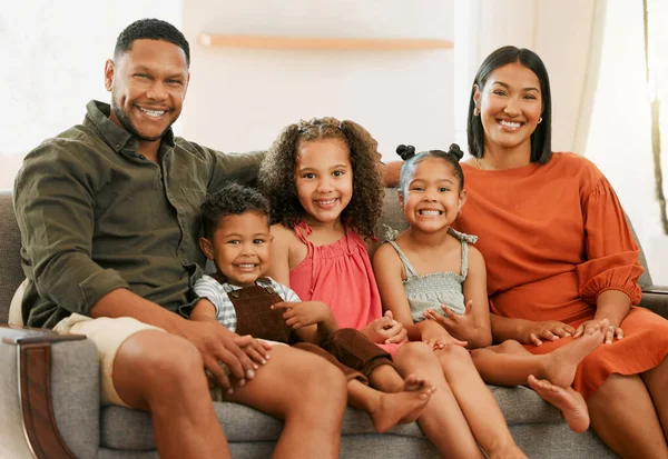 Portrait of a mixed race family of five relaxing on the sofa at home. Loving black family being affectionate on the sofa. Young couple bonding with their adopted kids at home.