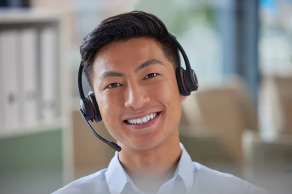 Closeup portrait of friendly Asian businessman working in a call center. Financial advisor wearing a headset with microphone. Customer service rep answering calls. Hotline and help desk.