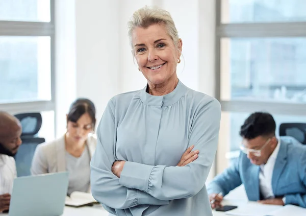 I always motivate my team to achieve the greatest. Portrait of a mature businesswoman standing with her arms crossed in an office with her colleagues in the background