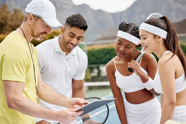 Ive worked out a strategy for all of you. a handsome mature male tennis coach using a tablet and talking strategy with his students out on the court