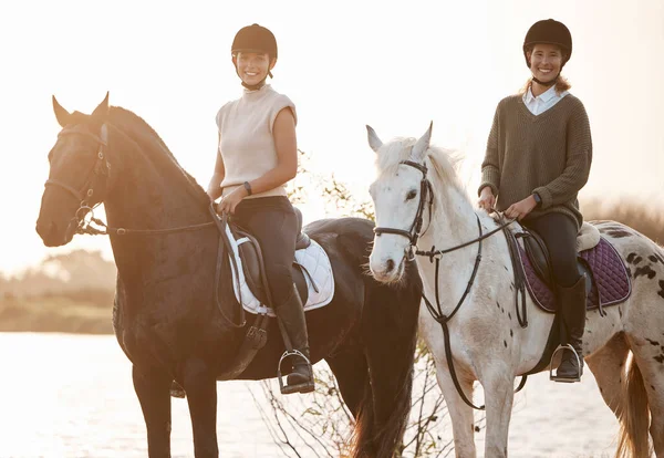 Horseback riding offers a different way to see the world. two young women out horseback riding together