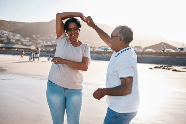 Lets dance like no ones watching. a mature couple spending time at the beach