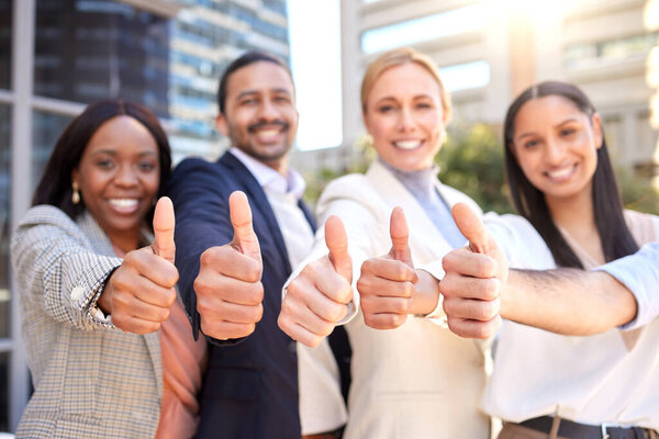 A thumb for every like. a group of businesspeople showing a thumbs up against a city background