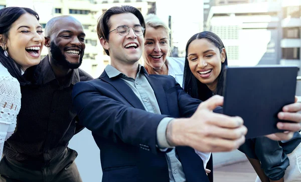 We make the dream work. a group of business colleagues taking selfies with a tablet outside