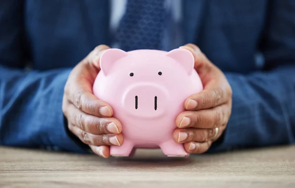 Being rich is having money being wealthy is having time. a unrecognizable man holding a piggy bank in a office