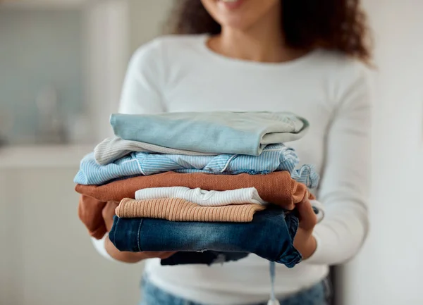 Woman cleaning a pile of laundry. Woman holding a stack of neat, folded clothing. Hands of a woman doing housework chores. Hispanic woman holding fresh, washed clothing and bedding