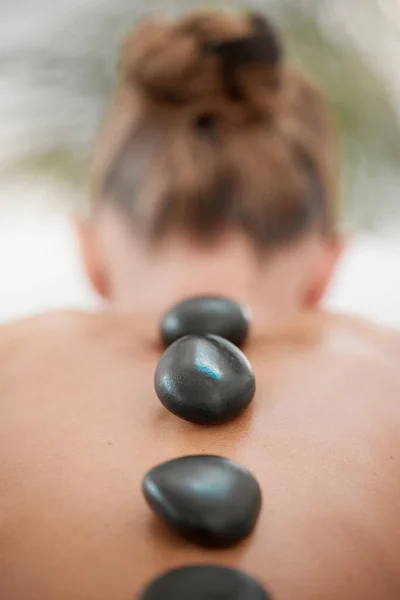 a woman resting with hot stones on her back during a trip to the spa.