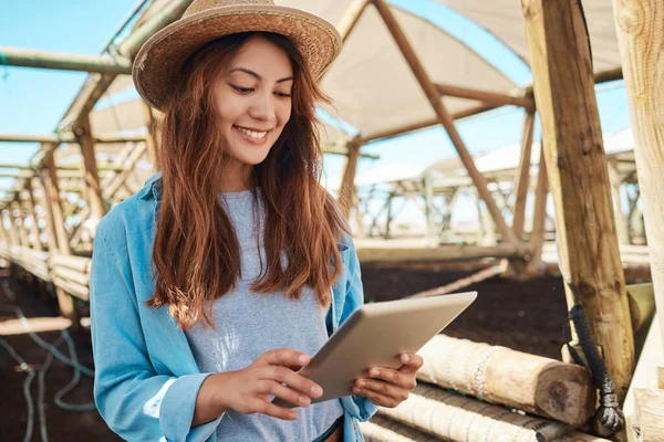 a young woman using a digital tablet while working on a farm.