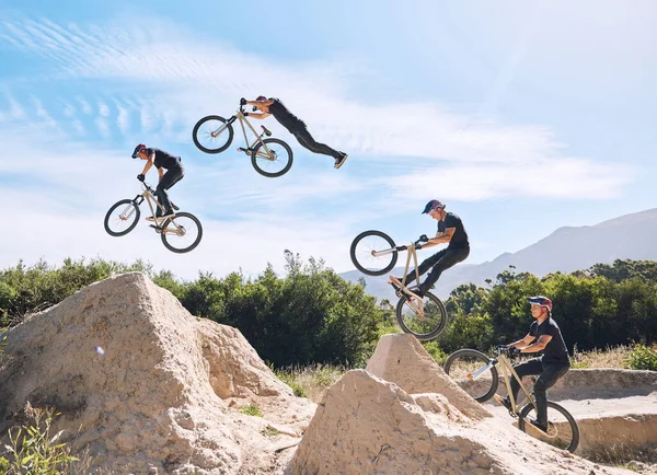 Young man showing his cycling skills while out cycling on a bicycle outside. Adrenaline junkie practicing a dirt jump outdoors. Male wearing a helmet doing extreme sports with a bike. Phases of a jump