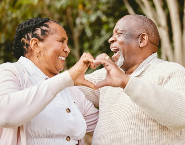 Theyre a perfect match. a senior couple forming a heart shape with their hands while sitting outside