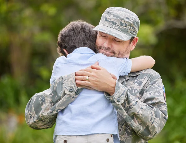 a father returning from the army hugging his son outside.