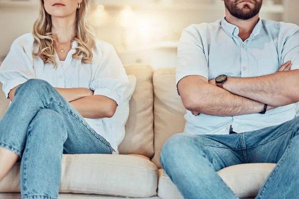 Unknown couple fighting and giving each other the silent treatment. Caucasian man and woman sitting on the sofa with their arms folded after an argument. Unhappy husband and wife ignoring each other.