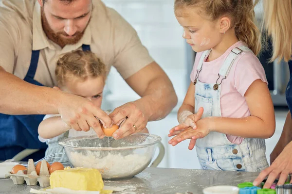Caucasian father helping little daughter crack an egg into a bowl while baking in the kitchen at home. Family being messy and having fun while preparing ingredients for cake batter or cookie dough.