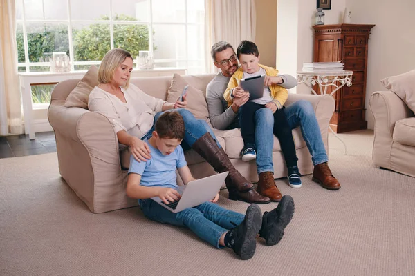 Welcome to the new way of bonding. a young family bonding while using their electronic devices together at home