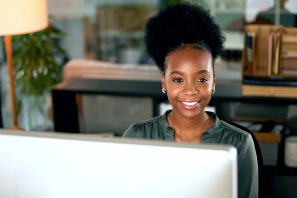 Smiling at what the future has to bring. a young businesswoman using a computer in an office at work