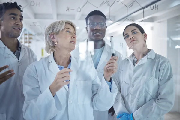 Diverse group of focused scientists talking while writing and planning together on a board at work. Team of serious lab workers sharing ideas and brainstorming while standing in a meeting together.