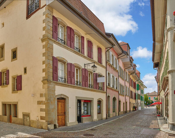 Street view of old buildings in a historic city with built medieval architecture and a cloudy blue sky in Annecy, France. Beautiful landscape of an empty small urban town with homes or houses.