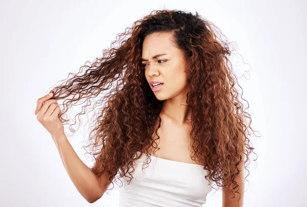 You think your lifes hard. a beautiful young woman looking frustrated with her hair while posing against a white background
