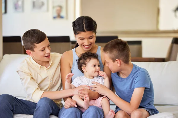 Multiracial family at home. Mother with her adoptive sons. Young mixed race mother relaxing with her children. Diverse blended family relaxing together at home. Boys spending time with their sister.