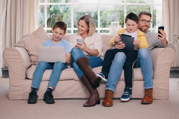 To each their own...DEVICE. a young family bonding while using their electronic devices together at home