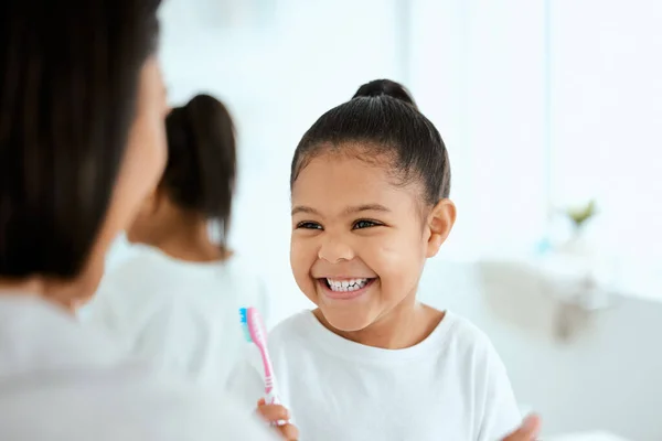 Big smiles with fresh breath. an adorable little girl brushing her teeth while her mother helps her at home