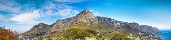 Panorama of Table Mountain and hills next to the ocean against a cloudy blue sky background with copy space. Scenic view of mother nature, sea and flora. The calm and beauty of mother nature.