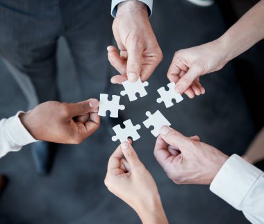 Success happens when everyone plays their part. five unrecognizable businesspeople building a puzzle in the office
