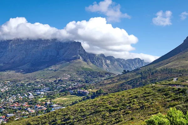 Panorama of a city near mountains in South Africa. Landscape of Cape Town suburbs beneath Table Mountain and a cloudy blue sky. Beautiful greenery and scenic nature near a rural town with copy space