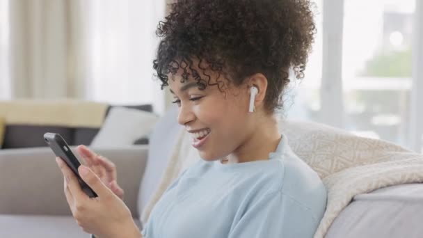 Жінка Транслює Музику Свій Телефон Одягаючи Бездротові Навушники Розслабляючись Вдома — стокове відео