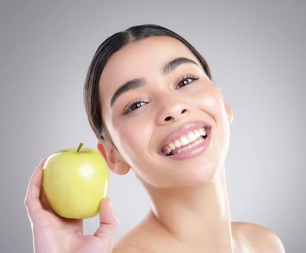 It starts with making a healthy choice. Studio portrait of an attractive young woman posing with an apple against a grey background