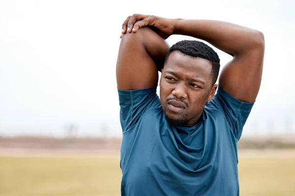 Stretching prompts your brain to switch into workout mode. a sporty young man stretching his arms while exercising outdoors