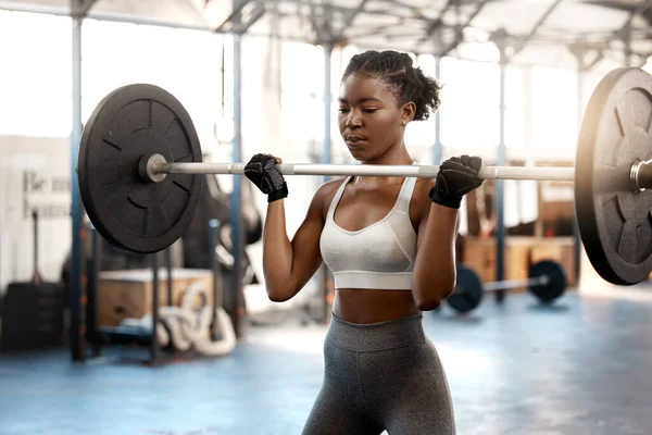 Strong women only intimidate weak men. a sporty young woman exercising with a barbell in a gym