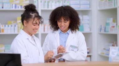Two female pharmacists use a checklist and discuss work in a pharmacy. Professional young chemists talk about prescription or chronic medication, taking notes, and working in a clinic or dispensary.