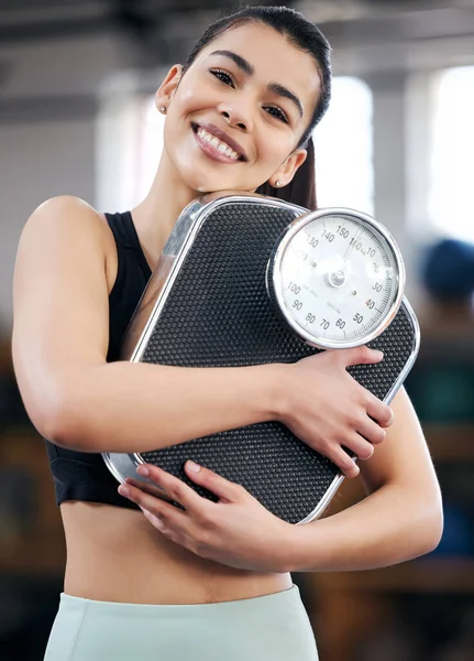 Lose weight, gain confidence. Portrait of a fit young woman holding a scale in a gym