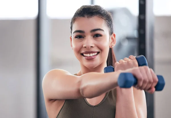 Feeling fit and looking fabulous. Portrait of a young woman working out with dumbbell weights in a gym