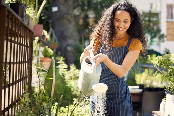 Giving them some attention. a young female florist watering plants at work